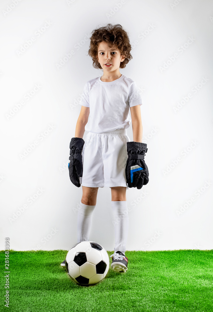 Boy with soccer ball on the green grass.Excited little toddler boy playing football on soccer field against light background. Active childhood and sports passion concept. Save space