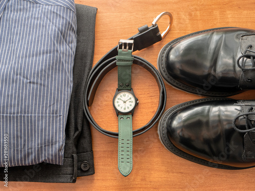 top view on businessman clothing set - pants, shirt, pair of black shoes, wrist watch and leather belt