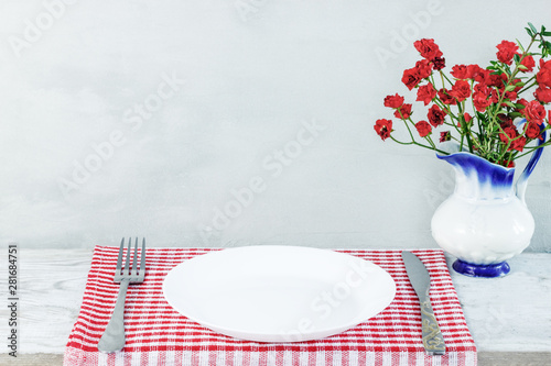 Empty plate on tablecloth or napkin on wooden table over cement background photo