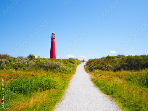 View of the North Tower - lighthouse in Schiermonnikoog islands one of the Frisian Islands, on sand dune against blue sky. Holland. Netherlands. Summer travel and vacation concept photo