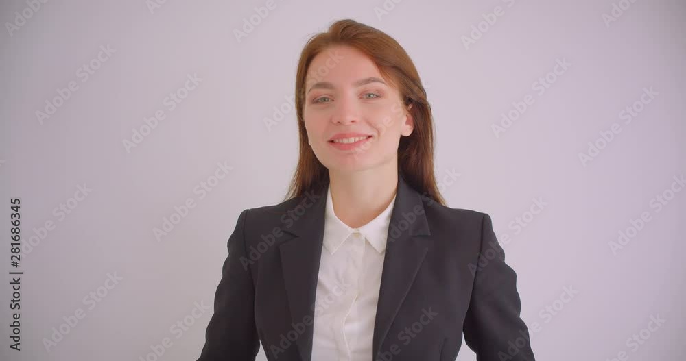 Closeup portrait of young caucasian businesswoman looking at camera smiling happily in the white apartment