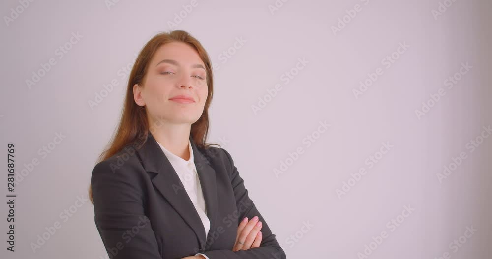 Closeup portrait of young caucasian businesswoman looking at camera smiling happily with her arms crossed over chest in the white office Closeup portrait of young caucasian businesswoman looking at camera smiling happily with her arms crossed over chest in the white office