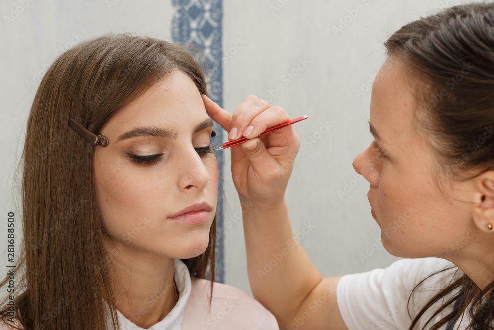 Makeup artist glues bunches on the eyelashes model.