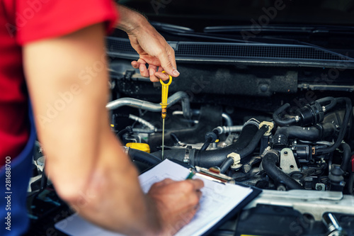 car inspection and maintenance - mechanic check engine oil level and writing in checklist