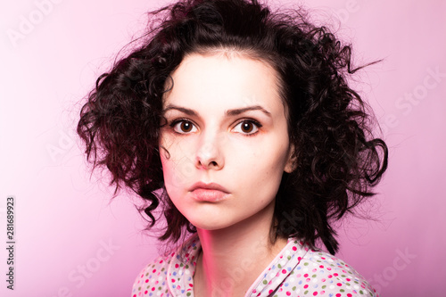 beautiful curly girl in pajamas, pink background