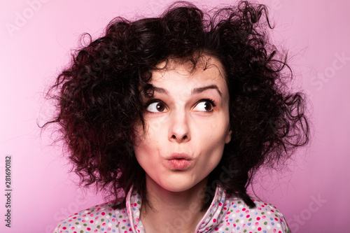 beautiful curly girl in pajamas, pink background