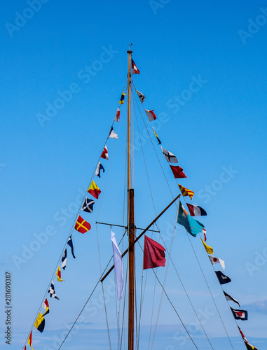 Mast with signal flags against blue sky.
