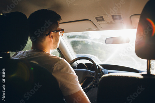 Young man driving a car in the setting sun