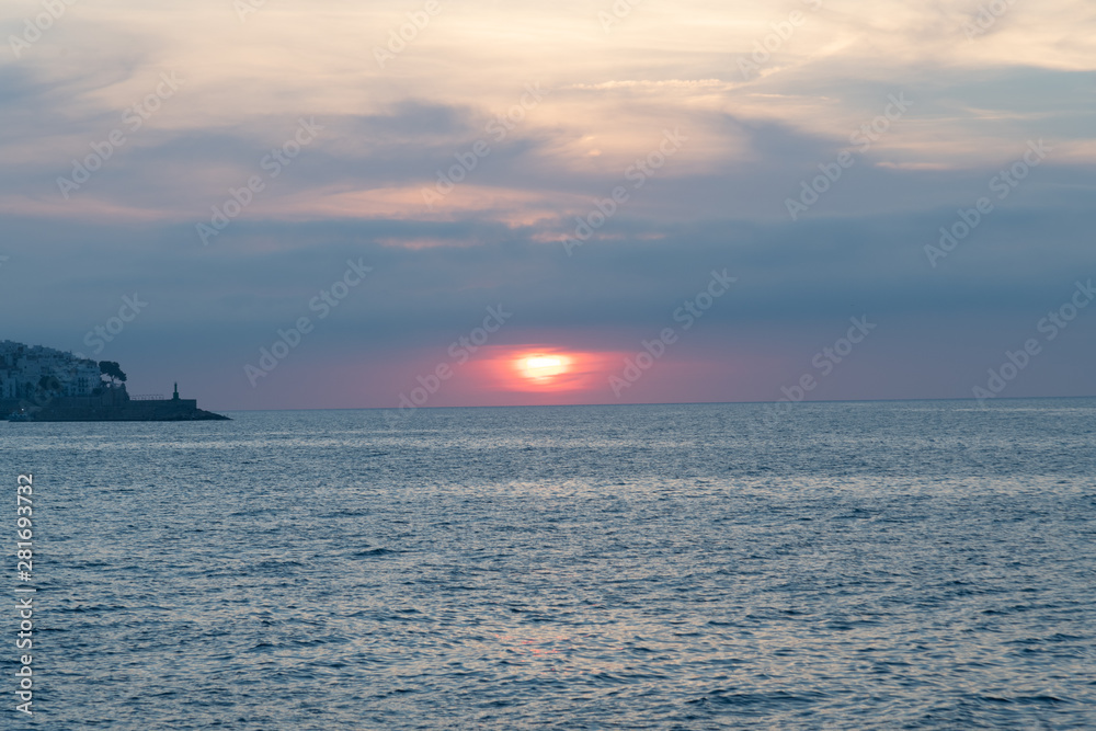 Blue photo of a calm sea landscape with sunset - Cloudy sky landscape over the sea and a lighthouse on an island