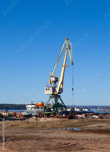 Crane in the port of machinery and forklifts to load and unload pallets on a sunny summer day