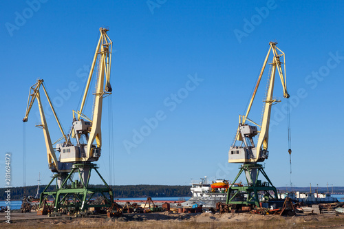 Cranes in the port of machinery and forklifts to load and unload pallets on a sunny summer day