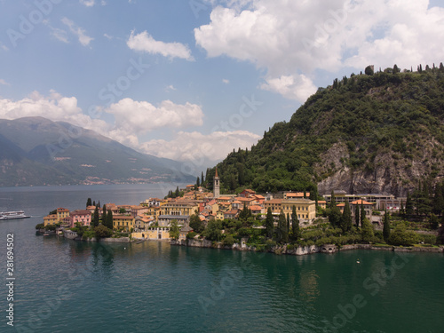 Beautifull aerial panoramic view from the drone to the Varenna - famous old Italy town on bank of Como lake. High top view to Water landscape with green hills, mountains and city in sunny summer day.