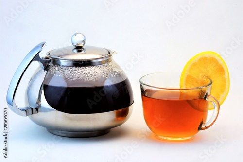 Tea in a Cup and a teapot with lemon. Helpful tea is popular refreshing drink obtained by boiling and macerating the leaf of the tea Bush. Lemon-citrus, sour taste, vitamins and cooking.