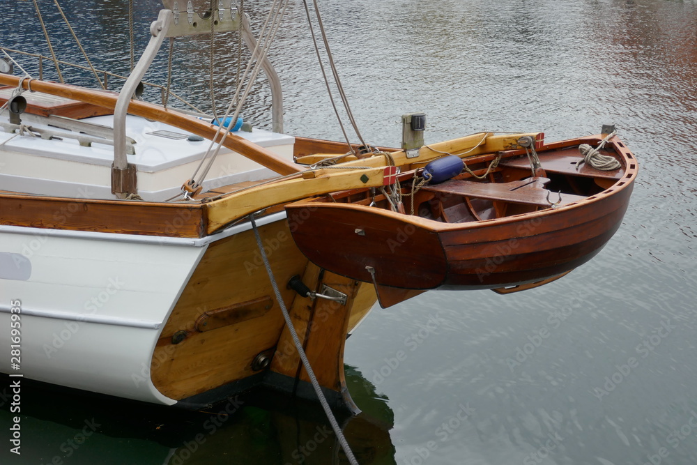 Dinghy, small rowing boat made of mahogany wood, attached to the stern of a sailing yacht