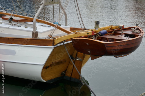 Dinghy, small rowing boat made of mahogany wood, attached to the stern of a sailing yacht © anela47