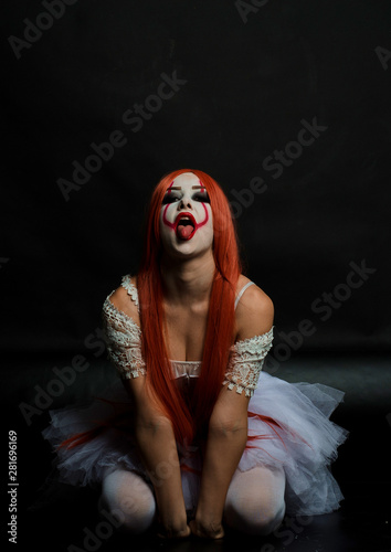girl with red hair in clown costume on black background