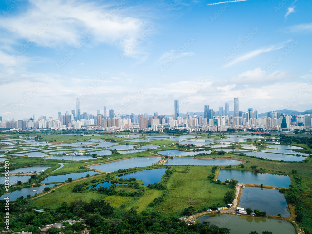 Rural green fields with fish ponds between Hong Kong and skylines of Shenzhen,China