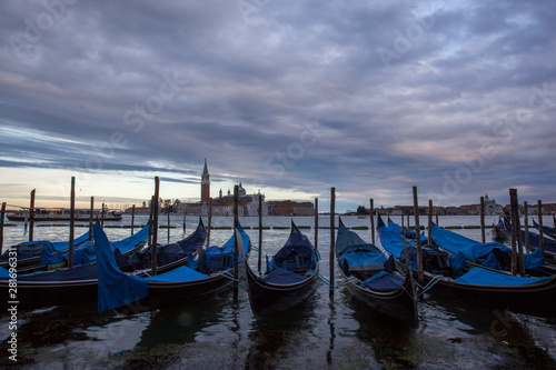 Gondolas in Venice at dusk taken on the shoreline besides the Piazza San Marco / St Marks Square.The image was taken during a dramatic sunset.
