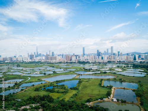 Rural green fields with fish ponds between Hong Kong and skylines of Shenzhen,China