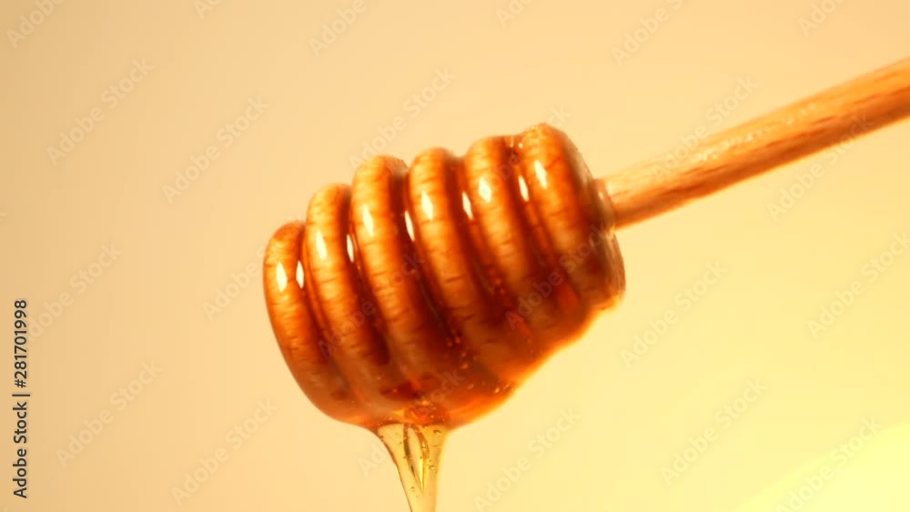 Honey drizzling from wooden honey dipper Honey drizzling from wooden honey dipper