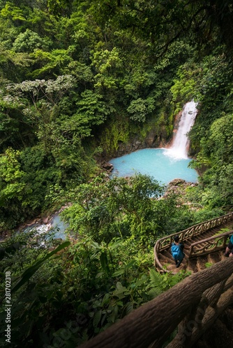 A young man walking down the stairs of the Rio Celeste Waterfall with a blue backpack, Alajuela, Costa Rica.