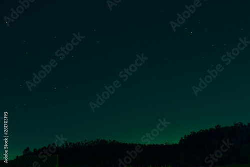 night forest silhouette under a beautiful starry sky with milky way and blue, green and yellow