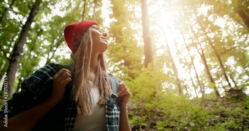 Female backpacker tourist looking up on trees and enjoying nature scenery, feeling free and relaxed, adventurer