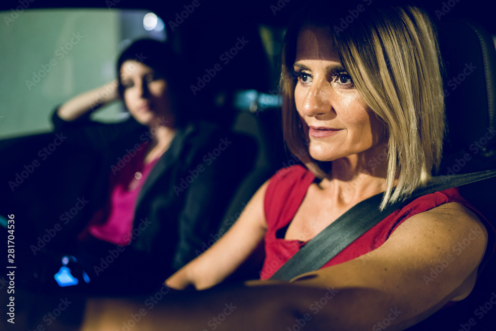 two women females in the car driving at night friends mother and daughter sisters travel journey road trip