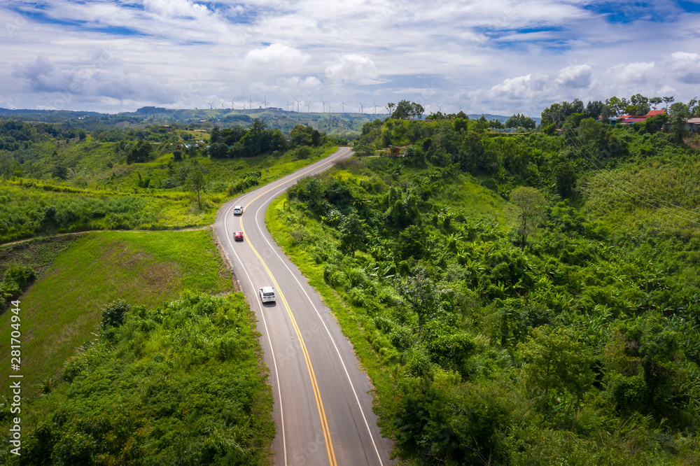 Aerial view over mountain road going through tropical rainforest landscape in Thailand..