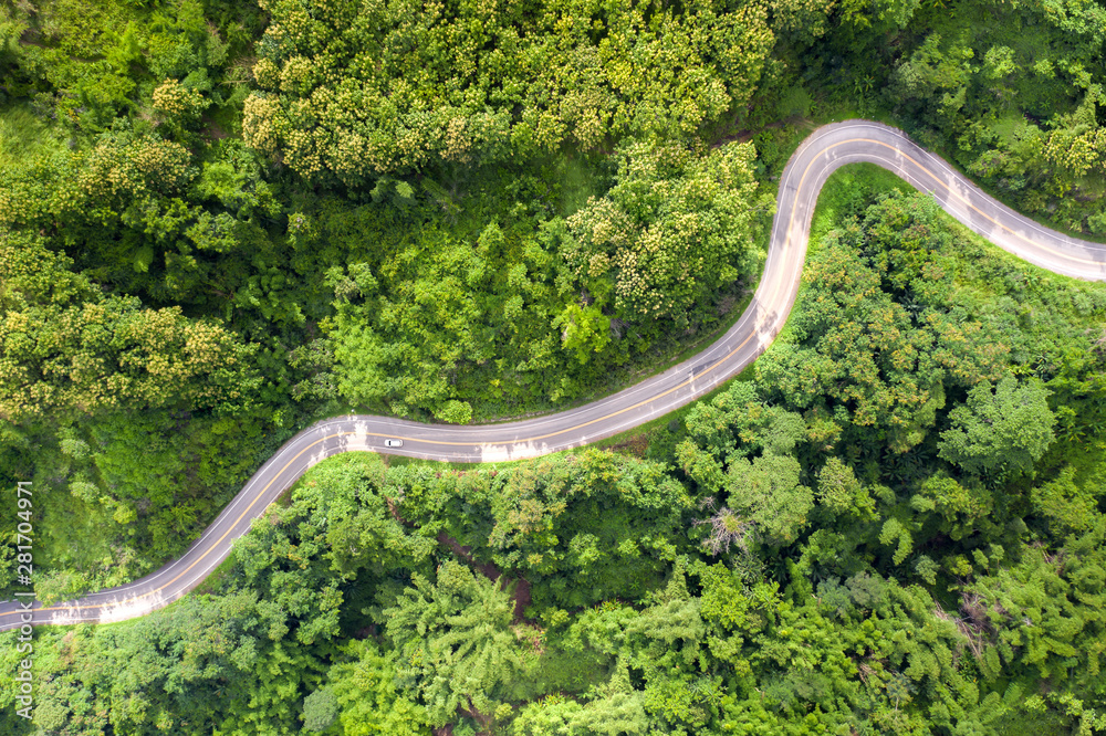 Aerial view over mountain road going through tropical rainforest landscape in Thailand..