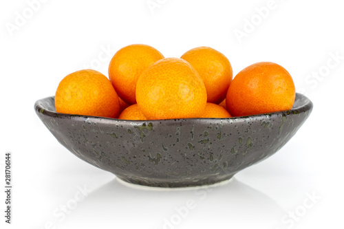 Lot of whole fresh orange kumquat arranged symmetrically in a dark ceramic bowl isolated on white background