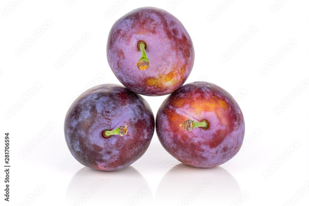 Group of three whole fresh blue plum arranged in a pyramid isolated on white background