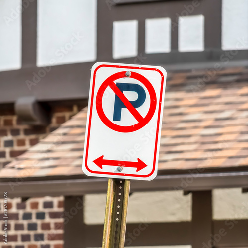 Square frame Close up view of a No Parking sign against a building on a sunny day