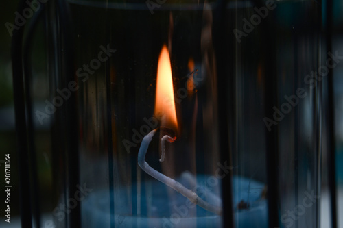 Closeup of burning candlewick in dark atmosphere, night time, outdoors