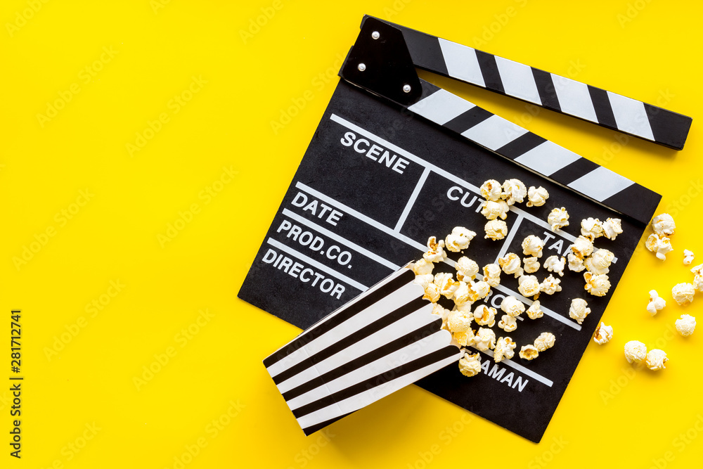 Naklejka premium Movie premiere concept with clapperboard, popcorn on yellow background top view space for text