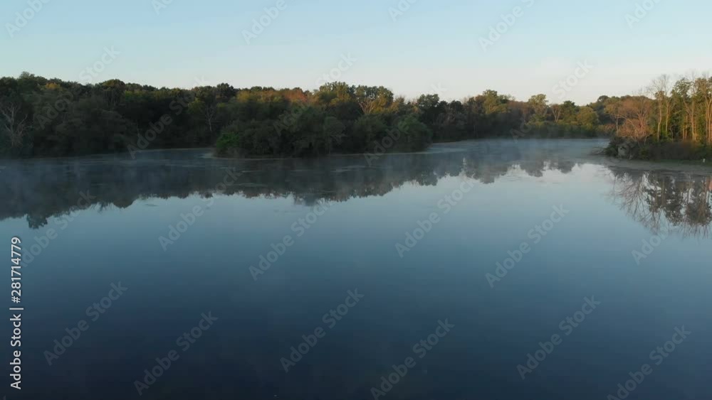 Aerial view, drone flying over water, mist, forest at sunrise. Summer, misty morning Aerial view, drone flying over water, mist, forest at sunrise. Summer, misty morning
