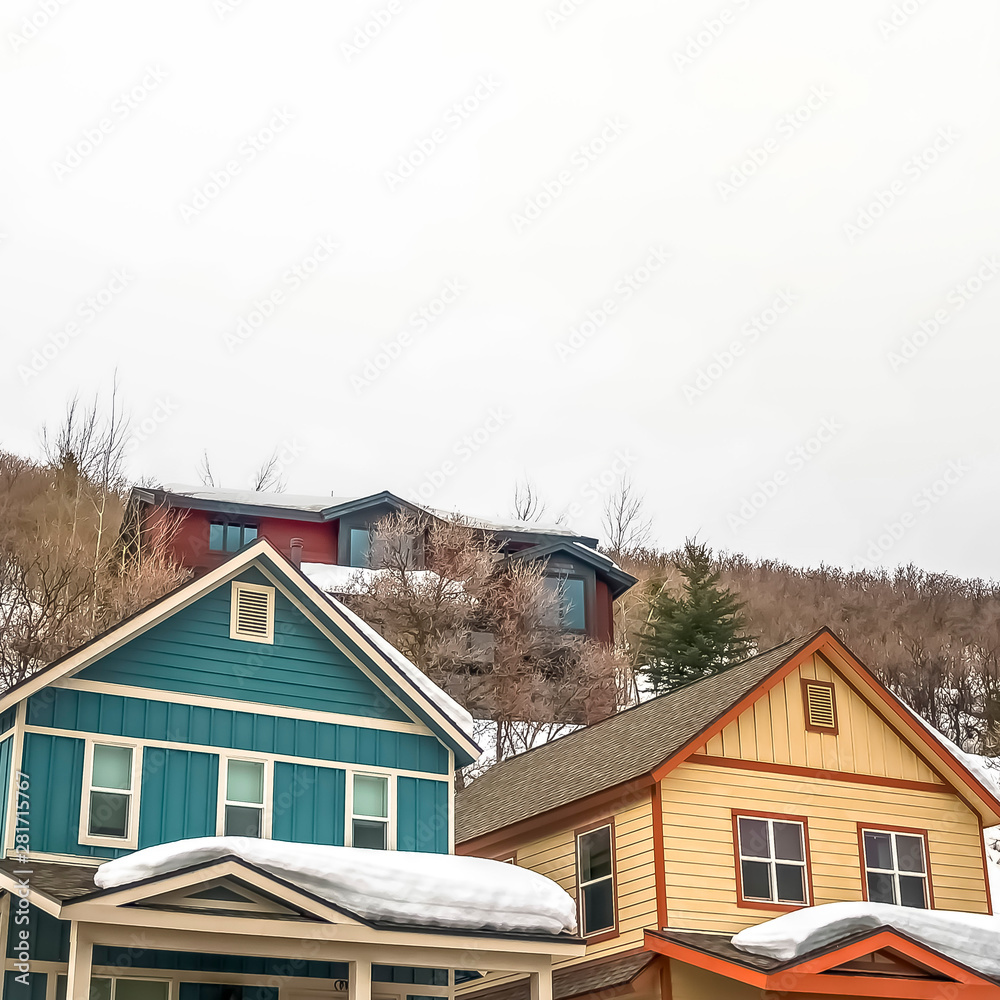 Square Facade of mountain homes with horizontal siding and balconies against cloudy sky Square Facade of mountain homes with horizontal siding and balconies against cloudy sky