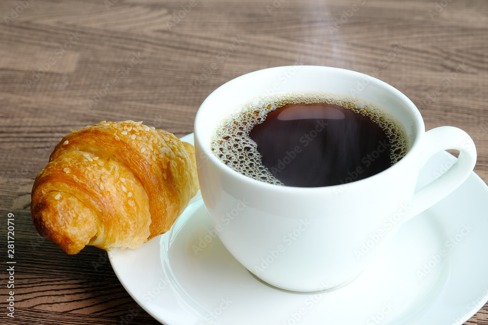 Hot coffee black and croissant Breakfast cereal and Wheat bread put on a wooden table at home Hot coffee black and croissant Breakfast cereal and Wheat bread put on a wooden table at home