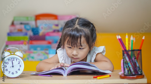 Little student girl  reading a book or doing homework at home .The decision of lessons. education and school concept.