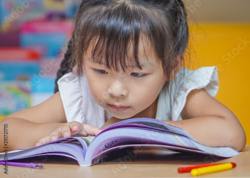 Little student girl  reading a book or doing homework at home .The decision of lessons. education and school concept.
