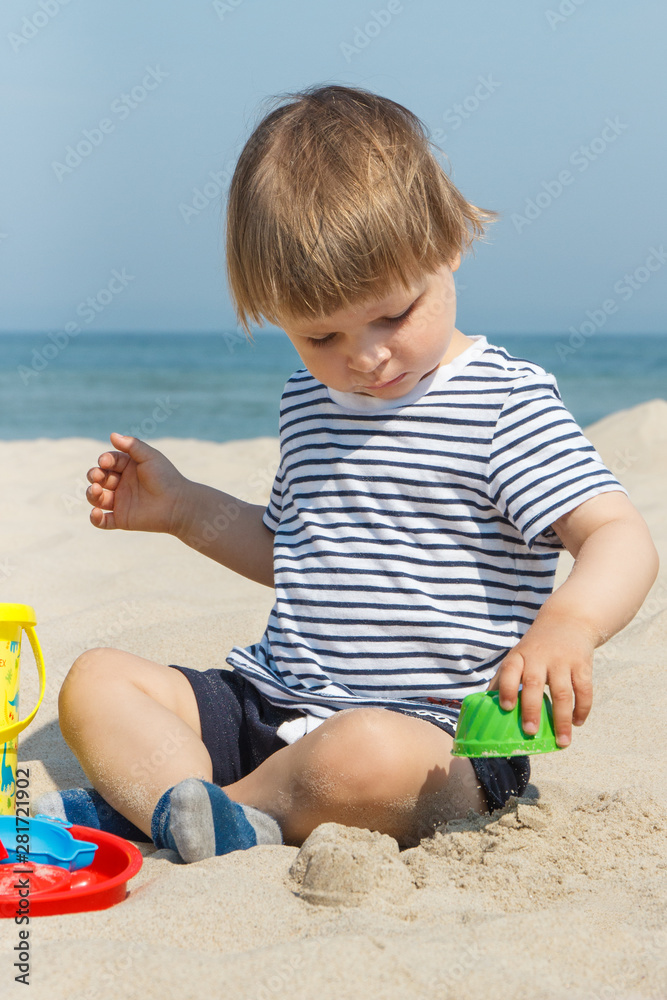Smiling boy playing on sand at beach. Summer, vacation and relaxation time concept Smiling boy playing on sand at beach. Summer, vacation and relaxation time concept