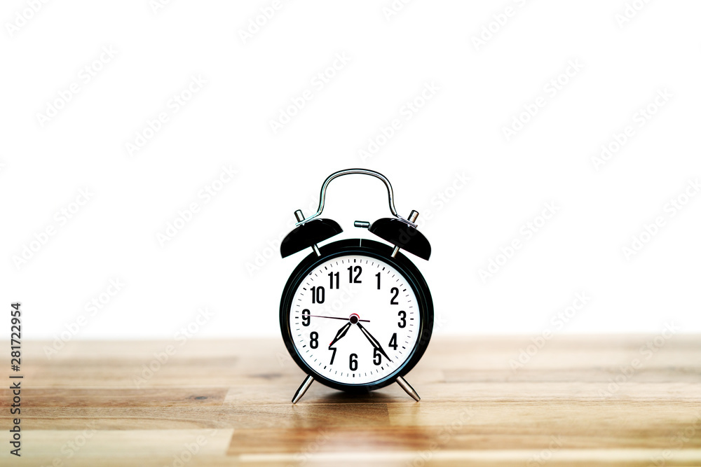 Black analog alarm clock on a wooden table Black analog alarm clock on a wooden table