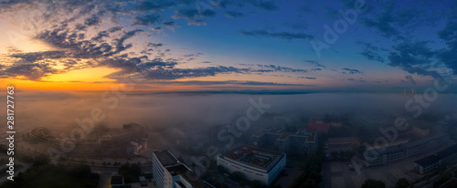 A beautiful sunrise as an aerial with a total view over fields, office buildings and a lake.