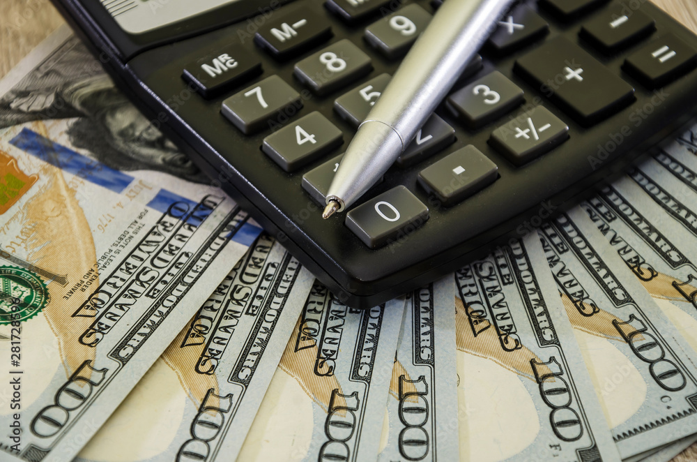 calculator, dollars and pen on a wooden background. Close-up. calculator, dollars and pen on a wooden background. Close-up.