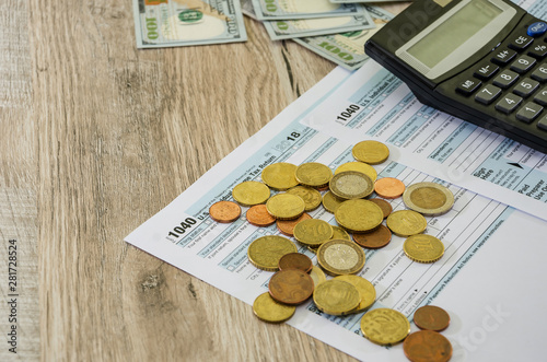 tax forms 1040, calculator and dollars on a wooden background, close-up