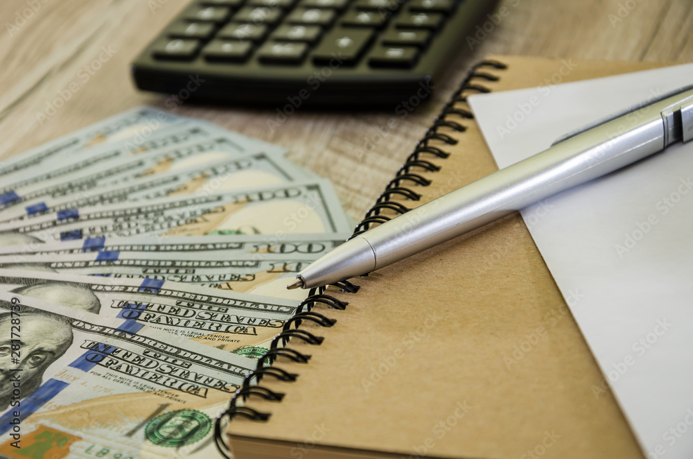 calculator, dollars notepad on a wooden background, close-up calculator, dollars notepad on a wooden background, close-up