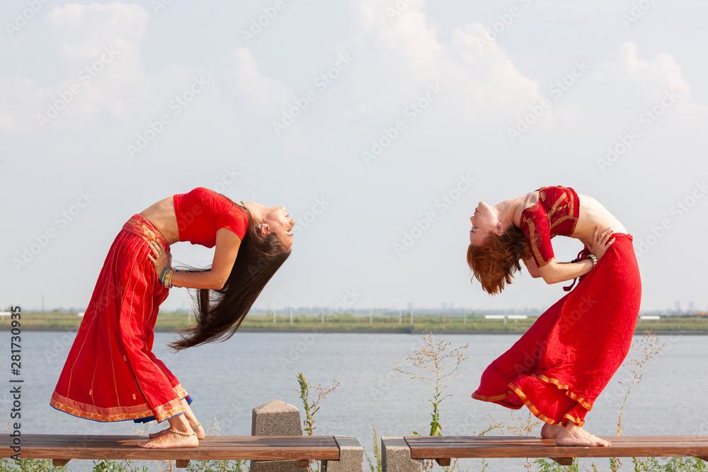 Pair of girls practice yoga. Women in a traditional saree.