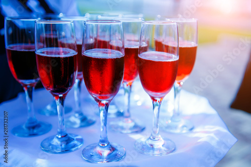 A row of glasses filled with cold champagne lined up, ready to be served. Glasses with Martini on the table - party background. Welcome drink on the wedding ceremony.