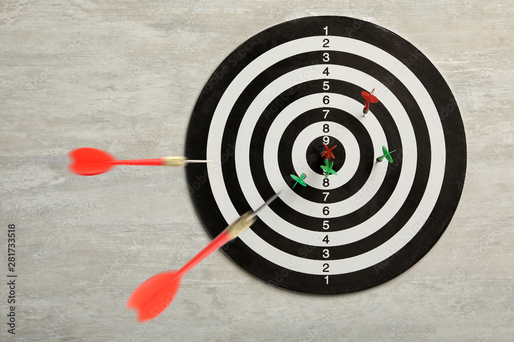 Dart board with color arrows on light stone background, top view. Space for text