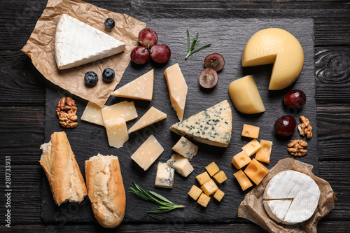 Flat lay composition with different types of delicious cheese on slate board photo